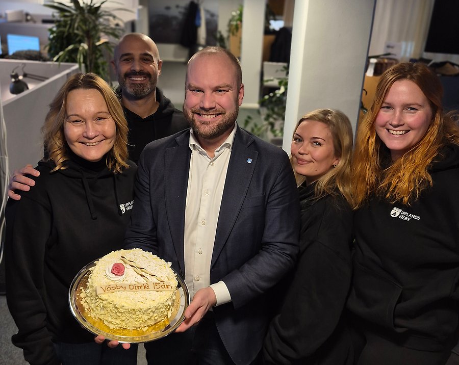 Fem personer står samlade runt en tårta med texten "Väsby Direkt 15 år".