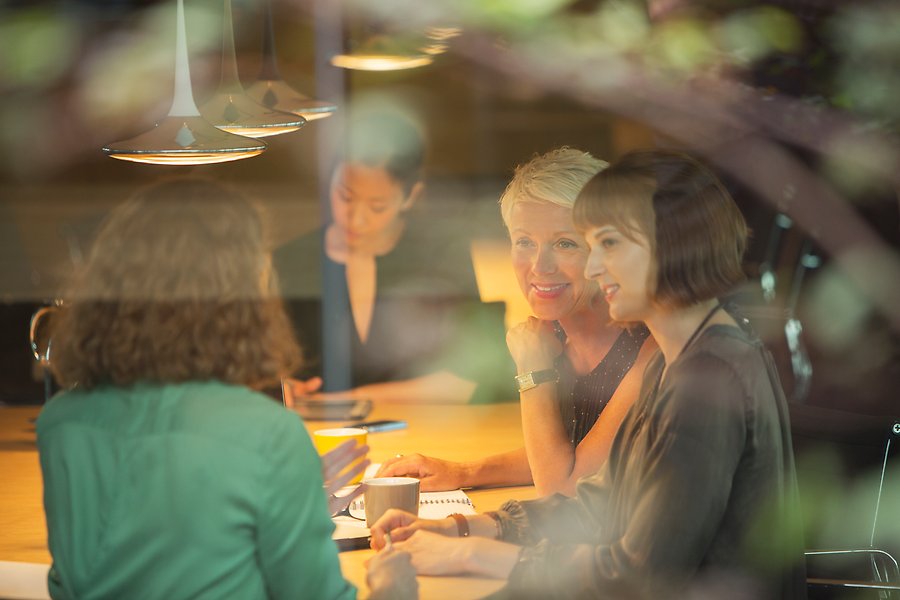 Några kvinnor sitter i ett kontorsmöte och samtalar.